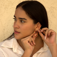 Load image into Gallery viewer, Mdel adjusting Salento earrings against a beige wall in Colombia